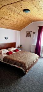 a bedroom with a large bed with a wooden ceiling at Casa langa rau in Bran