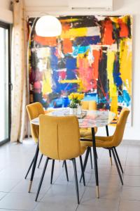 a dining room with a table and chairs in front of a painting at L'Avant Scène Meublé 5 étoiles Parking Gratuit Jacuzzi in Avignon