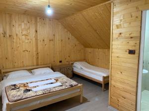 a bedroom with two beds in a wooden cabin at Bujtina Arlindi in Valbonë