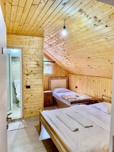 a bedroom with two beds in a wooden room at Bujtina Arlindi in Valbonë