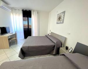 1 Schlafzimmer mit 2 Betten, einem Schreibtisch und einem TV in der Unterkunft B&B La Rosa in San Salvo