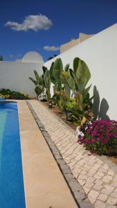 una piscina con plantas y flores junto a un edificio en Beachfront house,Manta Rota,Algarve, en Vila Nova de Cacela
