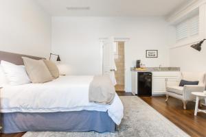 a white bedroom with a large bed and a kitchen at Beacon Hill in Carriage House at Oak Street Mansion in Kansas City