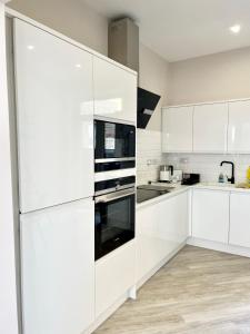 una cucina bianca con armadietti e elettrodomestici bianchi di Cliffs Pavilion 2 Bedroom Apartment a Southend-on-Sea