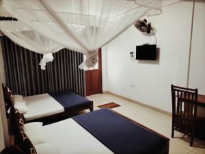 a bedroom with two beds and a television in it at Thilina Guest in Badulla