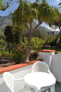 a white table and chairs on a patio with a tree at Cocos Park Ischia in Ischia