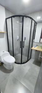 La salle de bains est pourvue d'une douche en verre et de toilettes. dans l'établissement HOTEL A & A SANTA ALEJANDRIA, à Medellín