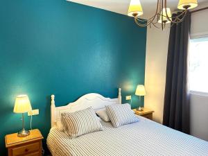 een slaapkamer met een bed met een blauwe muur bij Apartamentos Oasis de las Palmeras in Bolnuevo