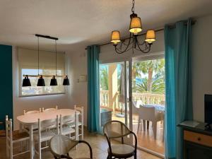 jadalnia ze stołem i krzesłami oraz oknem w obiekcie Apartamentos Oasis de las Palmeras w mieście Bolnuevo