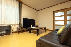 a living room with a couch and a television at Stay In Miyashita in Asahikawa