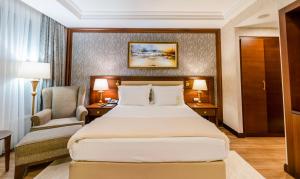 コジャエリにあるWellborn Luxury Hotelの大きなベッドと椅子が備わるホテルルームです。