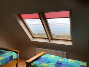 1 dormitorio con 2 camas y ventana en An teach Illanmore, en Portsalon