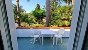 a white table and chairs on a balcony with palm trees at Cocos Park Ischia in Ischia