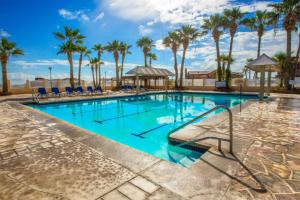 a swimming pool with blue chairs and palm trees at 2BR San Felipe Golf Course Condo in Playa El Paraíso