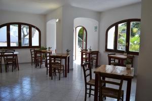 un restaurant avec des tables et des chaises en bois ainsi que des fenêtres dans l'établissement Cocos Park Ischia, à Ischia