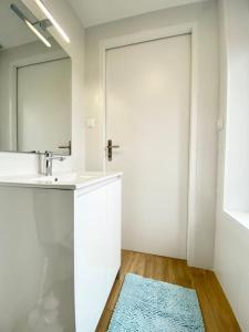 baño con lavabo, espejo y alfombra azul en Le Familik- Maison- CentreVille, en Licques