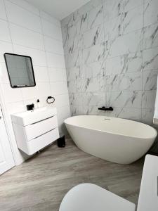 Baño blanco con bañera y lavamanos en Cliffs Pavilion 2 Bedroom Apartment en Southend-on-Sea