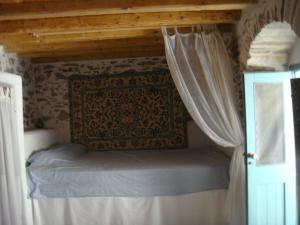 a bed in a room with a canopy and curtains at Παλιό κελάρι σε πέτρινο σπίτι in Áno Potamiá