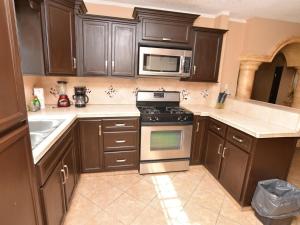 a kitchen with brown cabinets and a stove and microwave at Casa PortoBello - Intown home in San Felipe