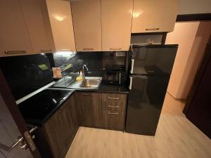 a kitchen with a black refrigerator and a sink at Vqra Sarafovo in Burgas