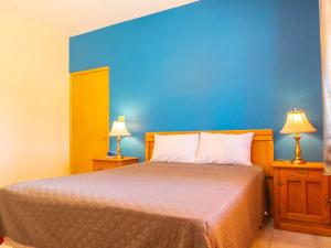 a bedroom with a bed with a blue wall and two lamps at 2BR /2BA Family Vacation Home with WiFi in Playa Hawaii +45 photos