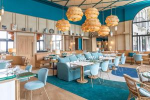 a dining room with tables and chairs and chandeliers at Hôtel Le Café de Paris in Biarritz