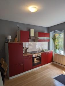 eine Küche mit roten Schränken und einem Herd in der Unterkunft Flensburg Zentrum 69 02 in Flensburg