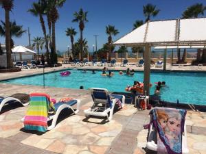 a pool with chairs and people in the water at 3-Bedroom El Dorado Ranch Rental with Beach View in San Felipe