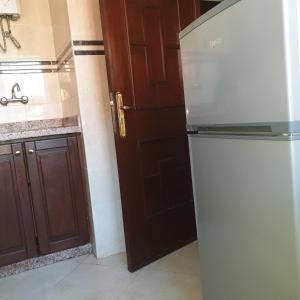 a kitchen with a refrigerator and a wooden door at Appartement Neuf à Louer sur Martil Maroc in Martil