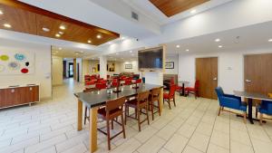 a dining room with tables and chairs and a flat screen tv at Holiday Inn Express South Burlington, an IHG Hotel in Burlington