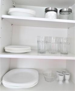 a white shelf with plates and glasses on it at Apartament Centrum Świnoujście in Świnoujście