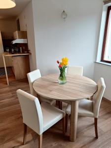 una mesa de comedor con sillas blancas y un jarrón de flores en Green Apartment Cerknica en Cerknica