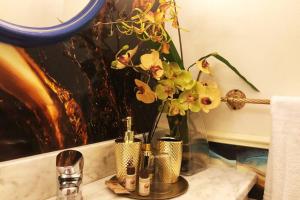 Un mostrador de baño con un jarrón con flores. en Rosymarty Apartment-vicino Firenze en Prato