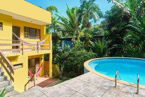 a house with a swimming pool next to a building at Studios na Vermelhinha in Ubatuba