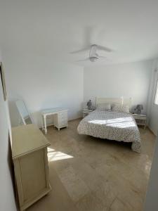 a white bedroom with a bed and a table at La Cala de Mijas Urb Alcantara in La Cala de Mijas