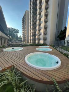 3 bañeras de hidromasaje en una terraza de madera con un edificio en Bello Horizonte Plaza - Apartamento, en Santa Marta