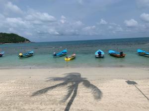a shadow of a person on the beach with boats in the water at The Black Sheep Hostel in Haad Rin