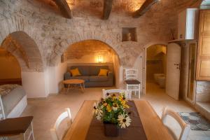 sala de estar con mesa y pared de piedra en Trullo Dell'Erba en Alberobello