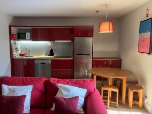 a living room with a red couch and a kitchen at Casa do Cruzeiro do Outeiro -comfort and tradition in Ponte de Lima