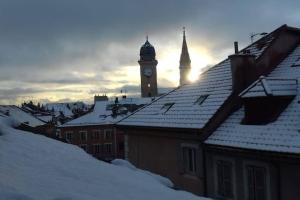 einen Uhrturm in einer Stadt mit schneebedeckten Dächern in der Unterkunft Appartement de caractère in Gap
