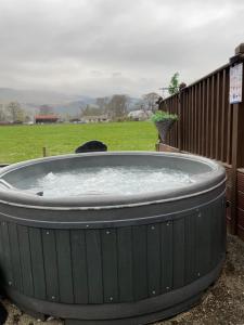 een hot tub in een tuin met een koe in een veld bij Ravenwood Lodge in Dollar