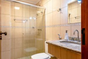 a bathroom with a shower and a toilet and a sink at Charmoso Apartamento no Centrinho de Capivari in Campos do Jordão