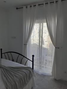 um quarto com uma cama e uma grande janela em Casa Rosa em Olhão