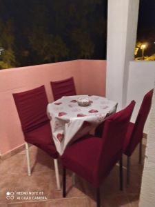 stół z czerwonymi krzesłami i białą tkaniną w obiekcie Apartments Stevović w mieście Herceg Novi
