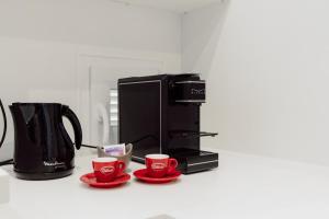 a black coffee maker and two red cups on a counter at Vittoria Suite in Campobasso