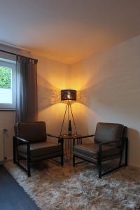 sala de estar con 2 sillas, mesa y lámpara en Mosel19 - Moderne, hochwertige Ferienwohnung en Niederfell