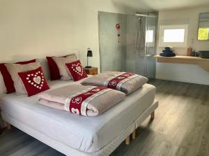 sypialnia z 2 łóżkami i białymi i czerwonymi poduszkami w obiekcie Gite Au sauna de l’Aubach w mieście Scherwiller
