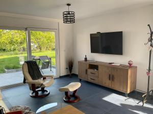 a living room with a flat screen tv and chairs at Gite Au sauna de l’Aubach in Scherwiller