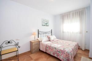 een slaapkamer met een bed, een stoel en een raam bij Bonito apartamento en Frigiliana in Frigiliana
