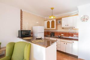 a kitchen with white cabinets and a green chair at Bonito apartamento en Frigiliana in Frigiliana